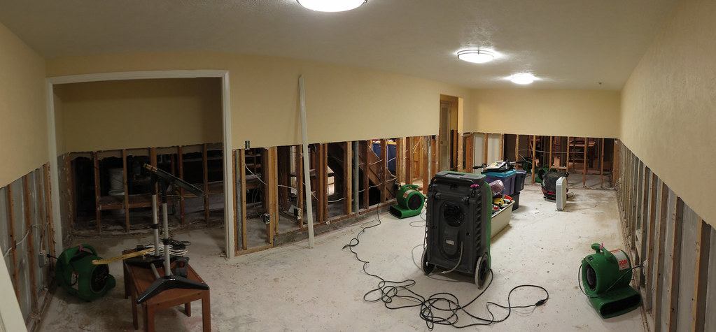 Basement with the lower drywall cut away, air movers and a dehumidifier running on the floor