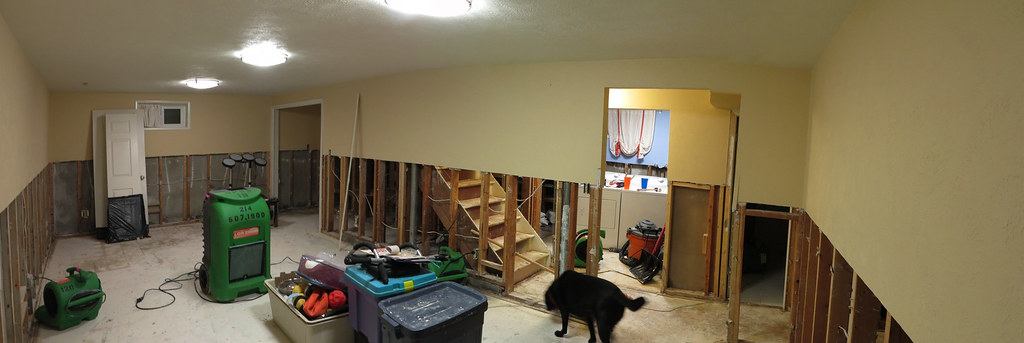 Finished basement with a flood cut along the walls, drying fans and a dehumidifier
