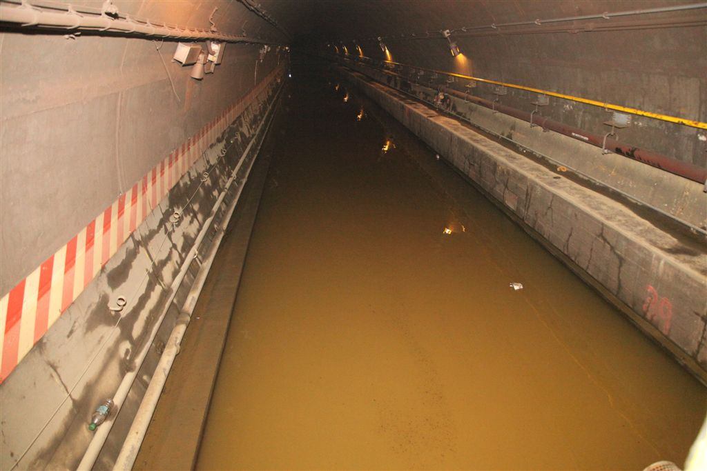 Subway tunnel filled with brown floodwater up to the walkway
