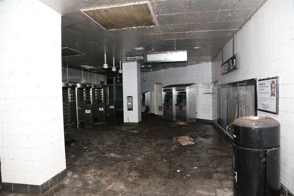 Subway station mezzanine with mud-covered floor and damaged ceiling after floodwater was pumped out